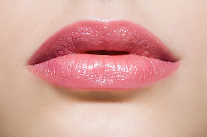 Close-up of woman's pink lips with gloss
