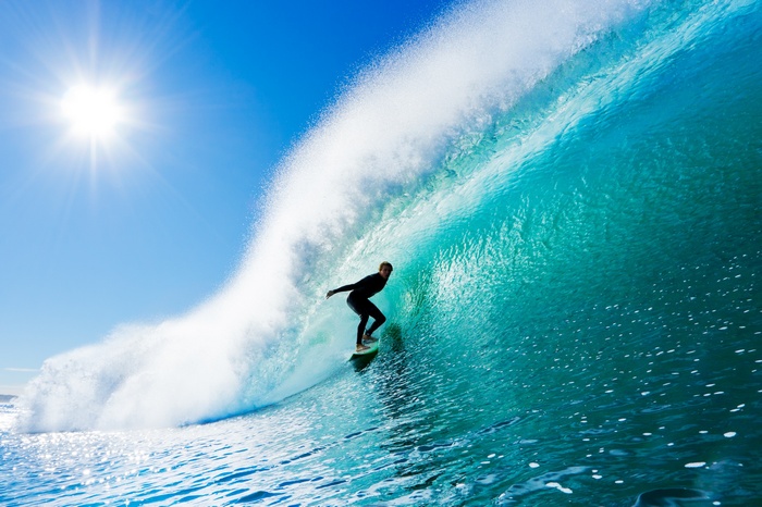 Surfer riding a large wave on a sunny day