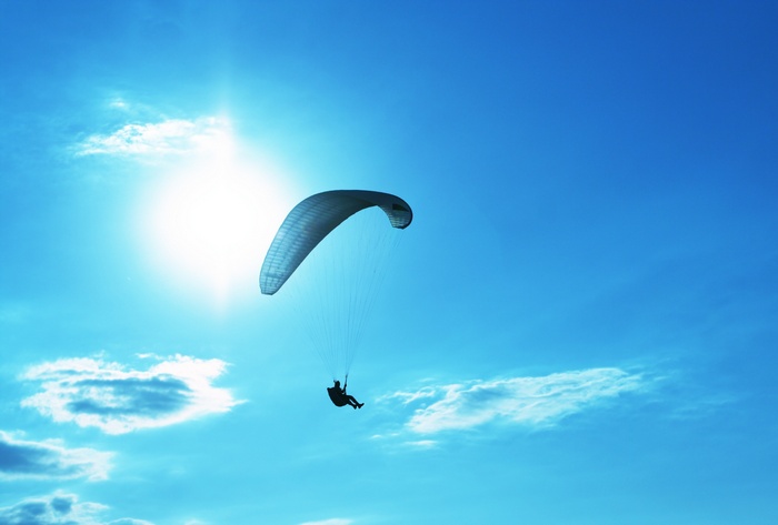 Paraglider soaring in the bright blue sky