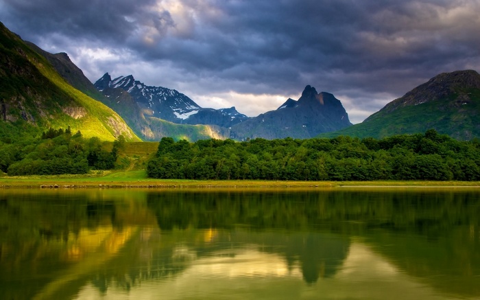 Mountain range reflected in a lake under stormy skies