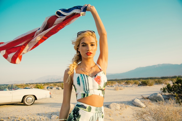 Pia Mia holding American flag in desert