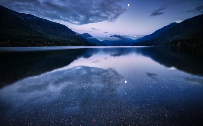Lake and mountains at dusk with moon reflection