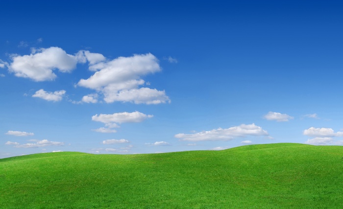 Green rolling hills under a blue sky with clouds