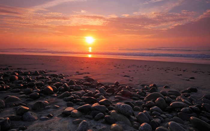 Sunset over a rocky beach with ocean waves