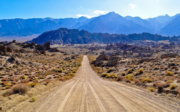 Dirt road leading to mountains in a desert landscape