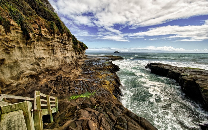 Wooden stairs leading to a rocky coastline with waves