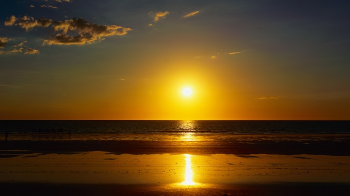 Sunset over the ocean with a beach in the foreground