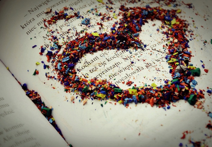 Heart made of colored pencil shavings on a book