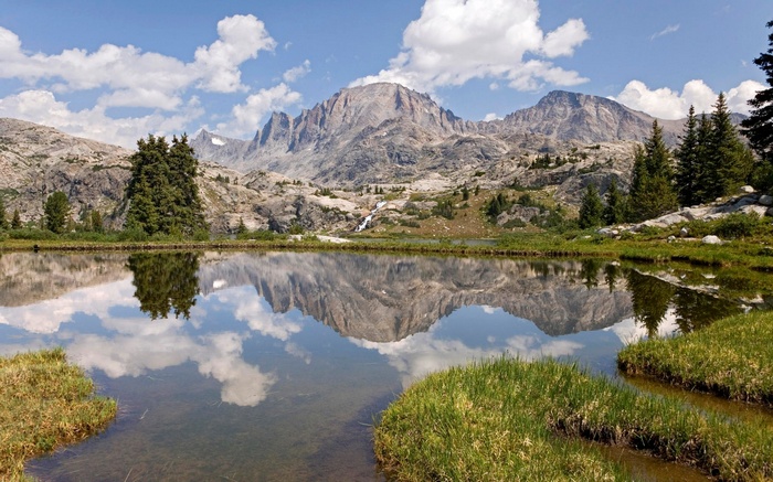 Mountain lake reflection with trees and clouds