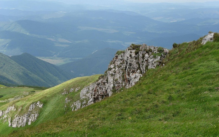 Rocky mountain ridge with green grass and distant hills
