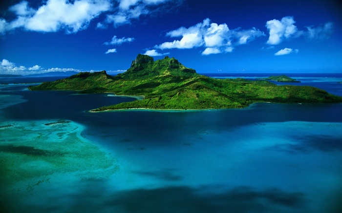 Aerial view of a tropical island with lush green mountains surrounded by turquoise water