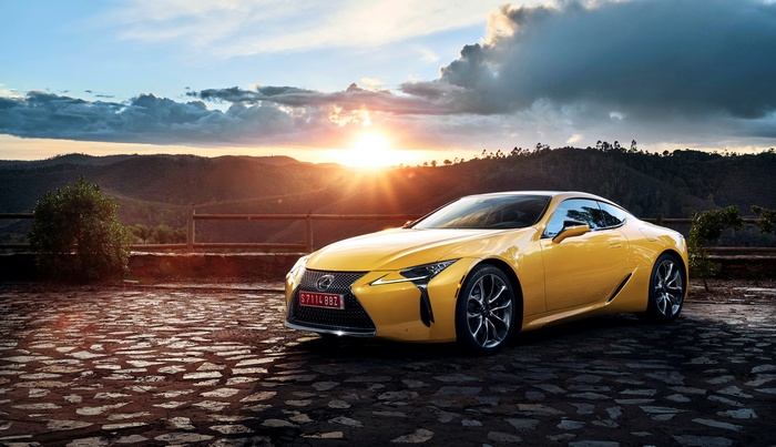 Yellow Lexus LC 500 on stone pavement at sunset