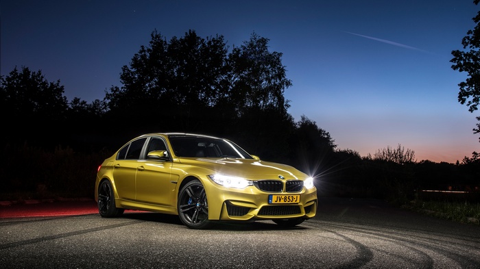 Yellow BMW M3 on a road at dusk