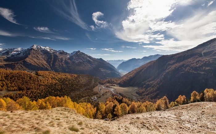 Autumn valley with snow-capped mountains and blue sky