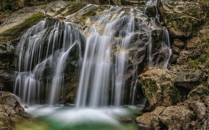 Waterfall cascading over mossy rocks into a pool