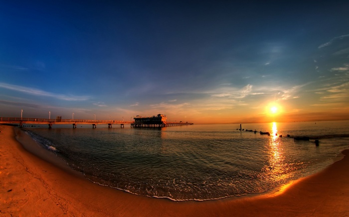 Sunset over the ocean with a pier and beach