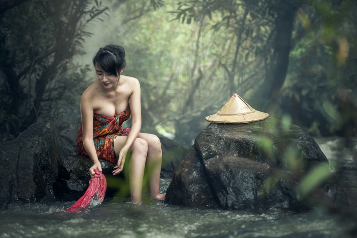 Asian woman washing clothes in a stream