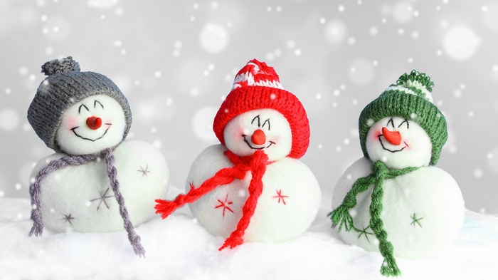 Three snowmen with hats and scarves in snowfall