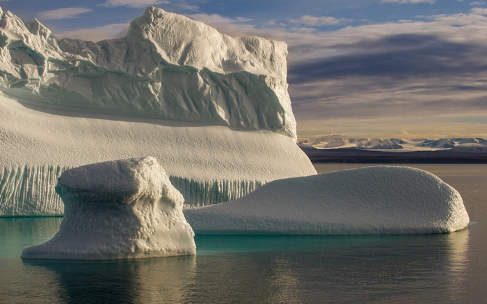 Icebergs floating in Arctic waters with mountains in background