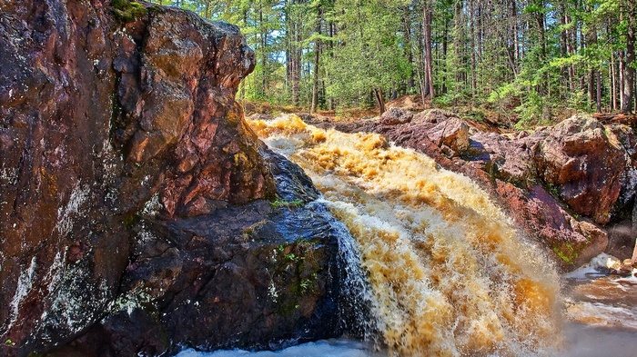 Brown waterfall cascading over rocks in a forest