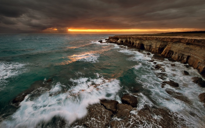 Stormy sunset over sea caves and rocky coastline