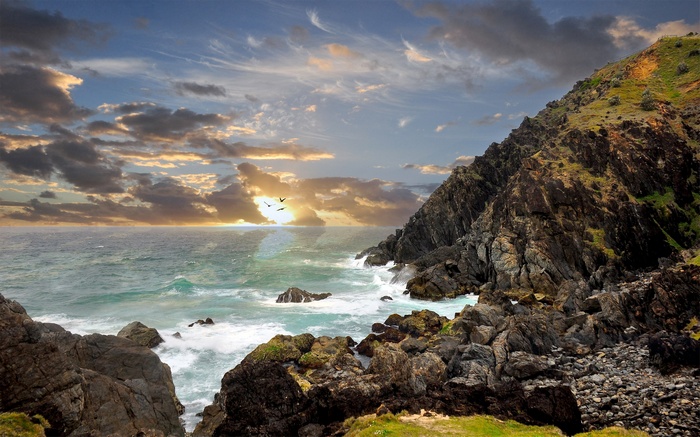 Rocky coastline with ocean waves and sunset sky