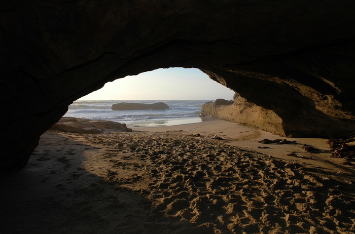 Cave entrance overlooking a beach and ocean