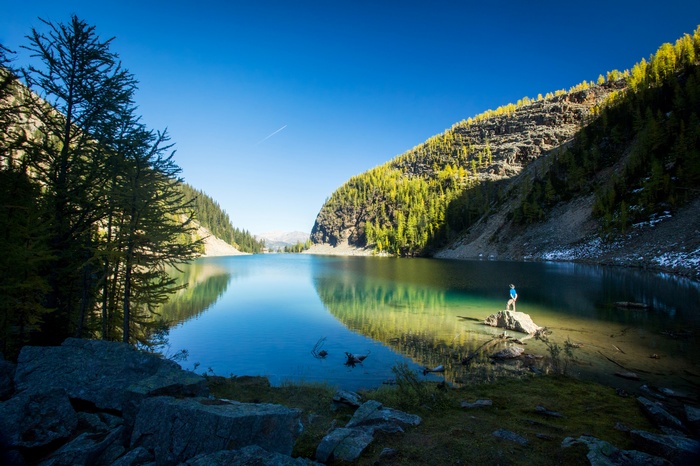 Man standing on rock in front of a lake in Banff National Park 4K