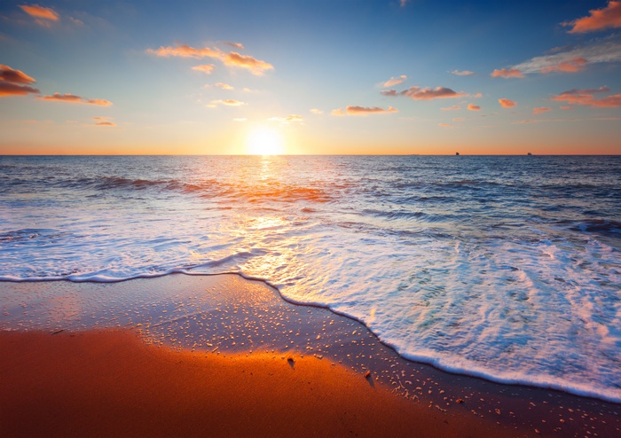 Sunrise over the ocean with waves on the beach