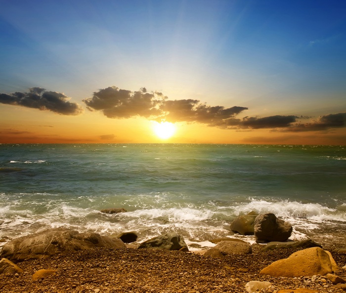 Sunset over the ocean with rocky beach