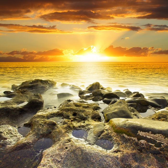 Sunset over a rocky beach with ocean waves