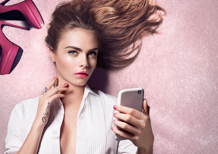 Cara Delevingne with pink heels and smartphone