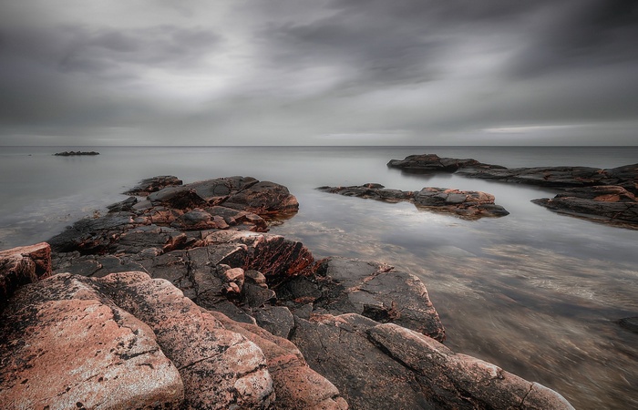 Rocky coastline with calm water under cloudy sky