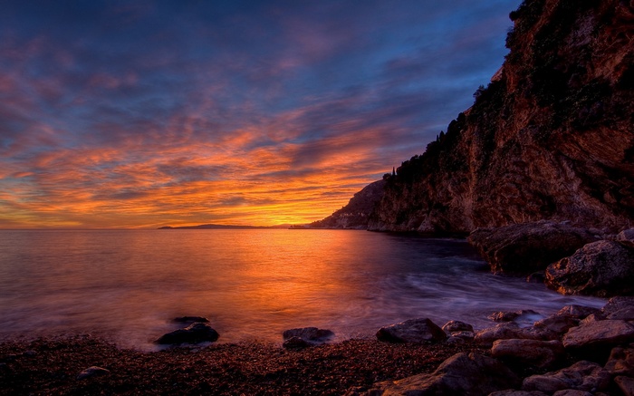 Sunset over a rocky coastline with calm water