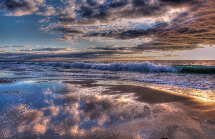 Ocean waves crashing on a sandy beach at sunset