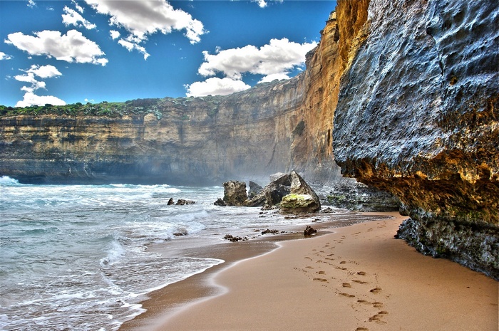 Footprints on a sandy beach with cliffs and ocean waves