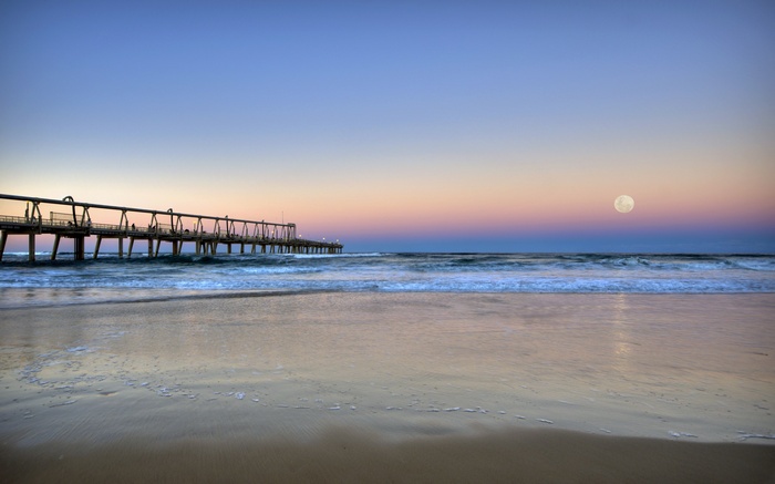 Pier over ocean at sunset with moon