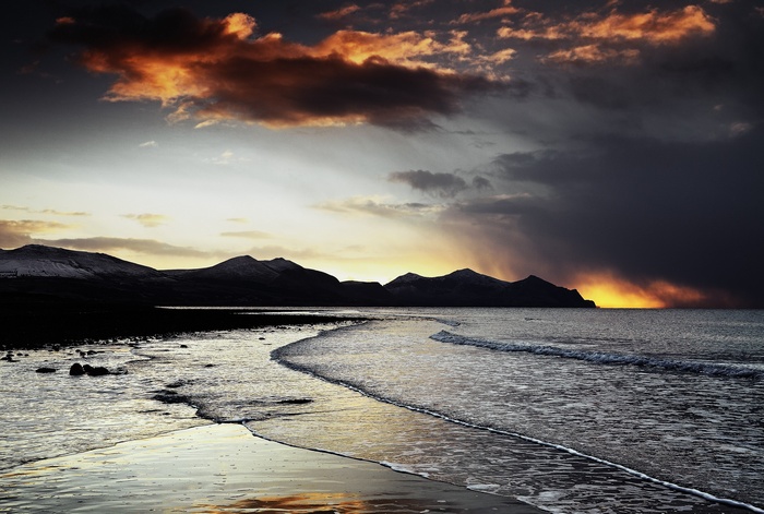 Dramatic sunset over a rocky beach and mountains