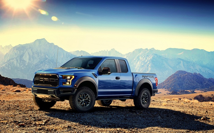 Blue Ford F-150 Raptor pickup truck in mountains
