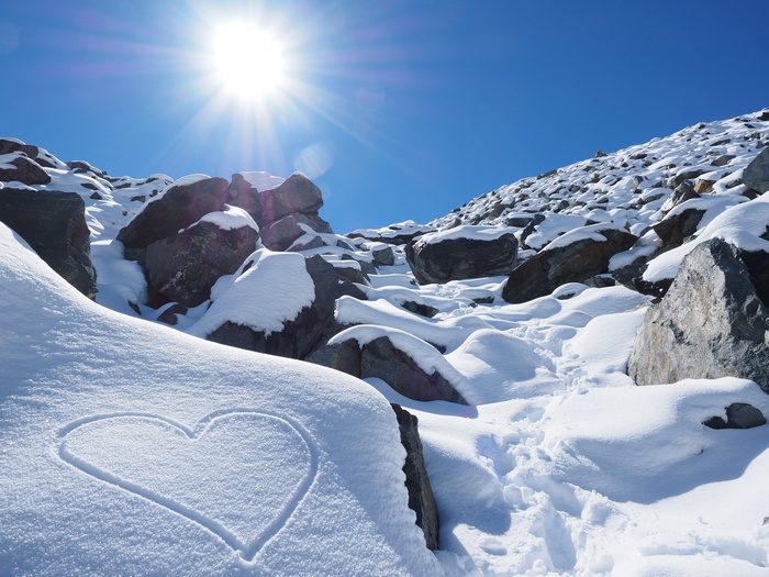 Heart drawn in snow on a rocky mountain slope
