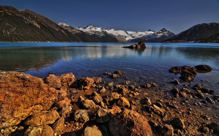 Rocky lake shore with snow-capped mountains