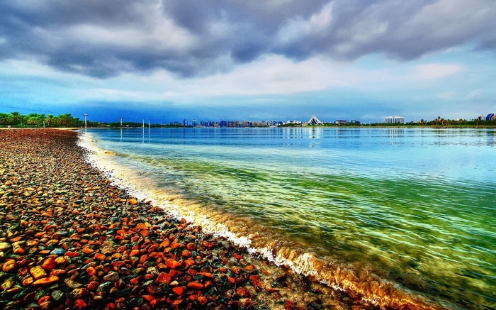 Pebble beach with calm water and city skyline
