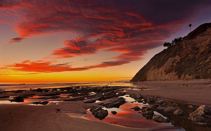 Sunset over a rocky beach with a cliff