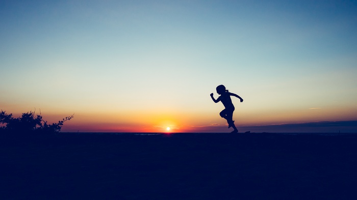 Silhouette of a child running at sunset