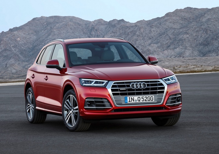 Red Audi Q5 SUV parked on asphalt with mountains in background