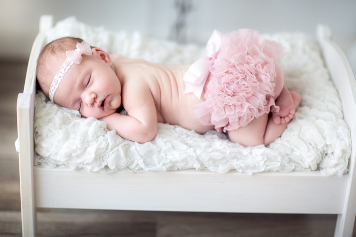 Newborn baby girl sleeping on a white bed