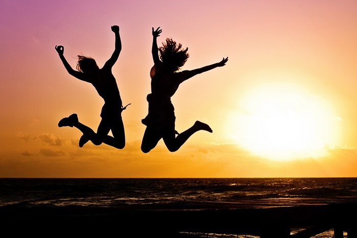 Two people jumping at sunset on the beach
