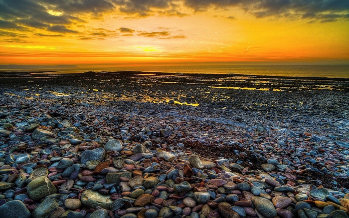 Rocky beach at sunset with ocean and clouds