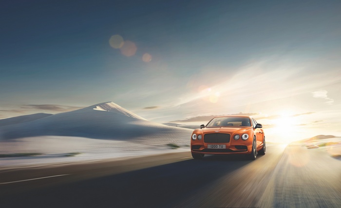 Orange Bentley Flying Spur W12 S driving on desert road