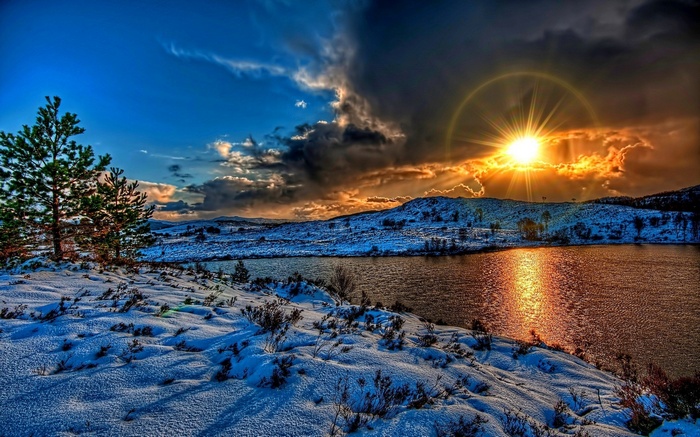 Snowy landscape with a lake at sunset